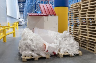 Kunststoffabfälle auf Palette vor Container im Produktionsumfeld